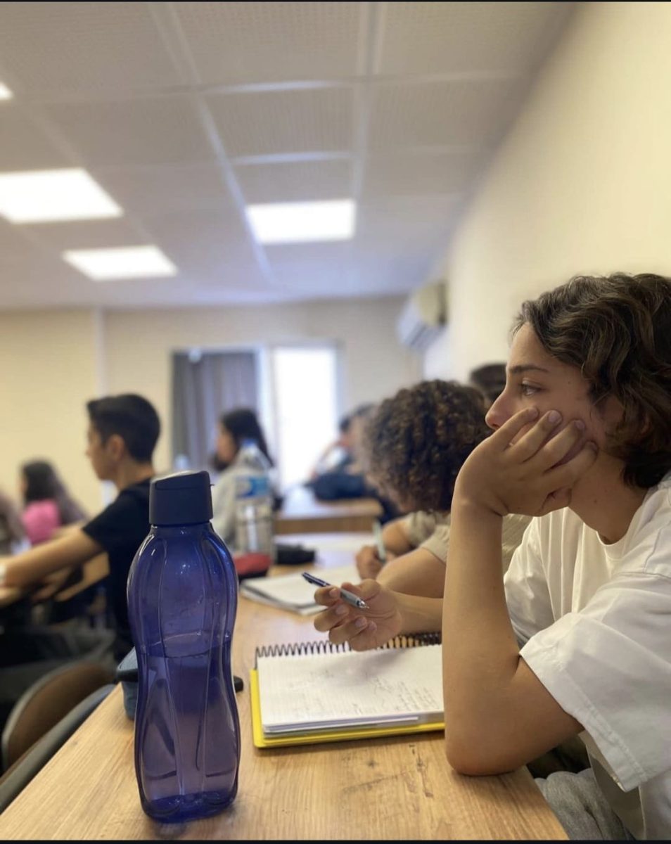 Sınıfta dersi dinleyip not alan öğrenci